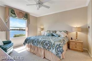 bedroom featuring light carpet, crown molding, ceiling fan, and a water view