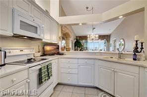 kitchen featuring white cabinetry, light tile patterned floors, a notable chandelier, kitchen peninsula, and white appliances