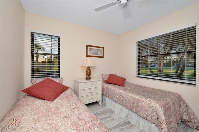 4366 27th Ct SW Unit 1-106, Naples, FL 34116 - bedroom with ceiling fan, marble look tiles, and a textured ceiling