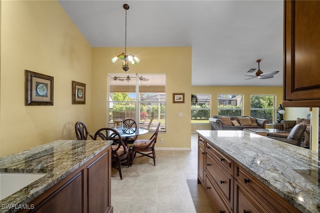 kitchen featuring light stone countertops, sink, decorative light fixtures, light tile patterned floors, and ceiling fan with notable chandelier