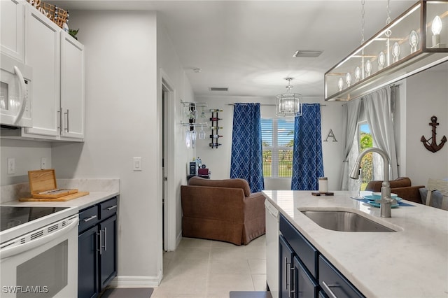 kitchen with white appliances, sink, pendant lighting, light tile patterned floors, and white cabinetry