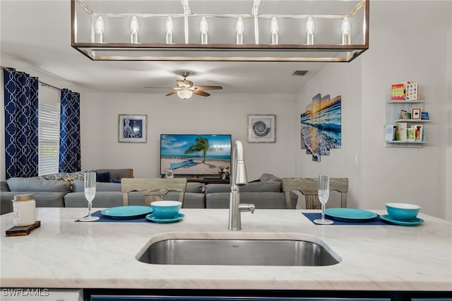 kitchen with ceiling fan, sink, and light stone counters