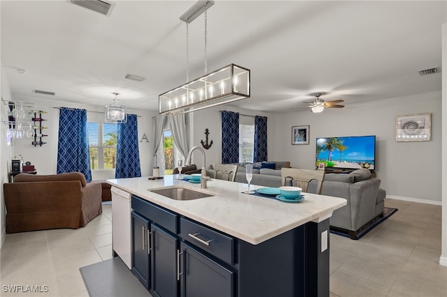 kitchen featuring white dishwasher, ceiling fan, a kitchen island with sink, sink, and hanging light fixtures