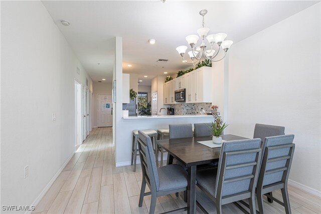 dining room with sink, light hardwood / wood-style flooring, and an inviting chandelier