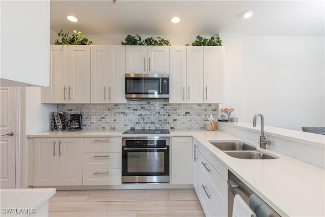 kitchen with decorative backsplash, white cabinetry, sink, and appliances with stainless steel finishes