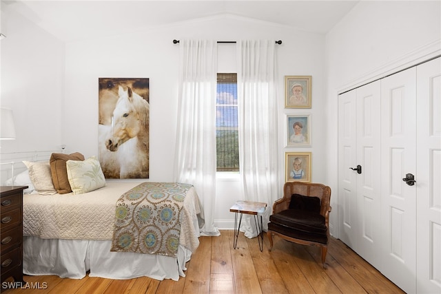 bedroom with a closet, light hardwood / wood-style flooring, and lofted ceiling