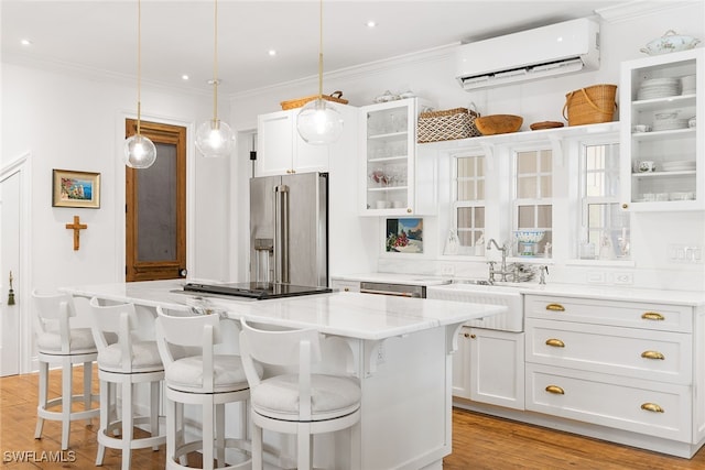 kitchen with an AC wall unit, white cabinetry, a kitchen island, and stainless steel appliances