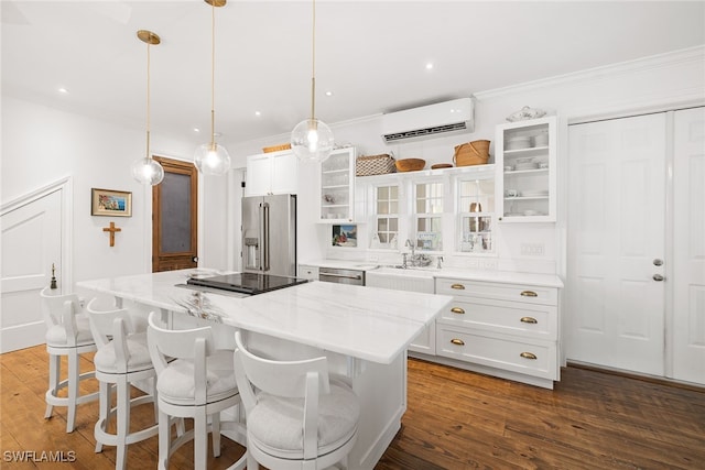 kitchen featuring a center island, stainless steel appliances, a wall mounted air conditioner, pendant lighting, and white cabinets