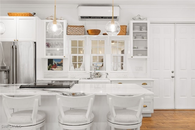 kitchen with a kitchen breakfast bar, hanging light fixtures, white cabinetry, stainless steel appliances, and a wall unit AC