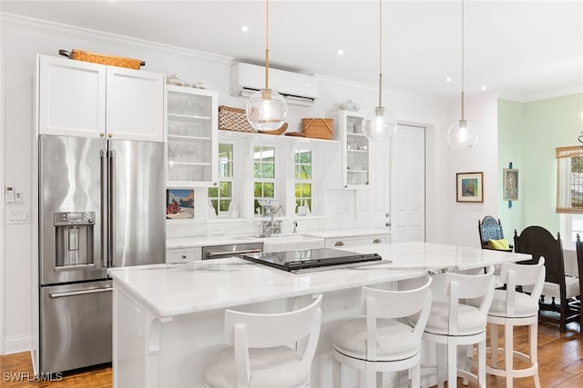 kitchen featuring white cabinetry, a center island, stainless steel appliances, pendant lighting, and light wood-type flooring