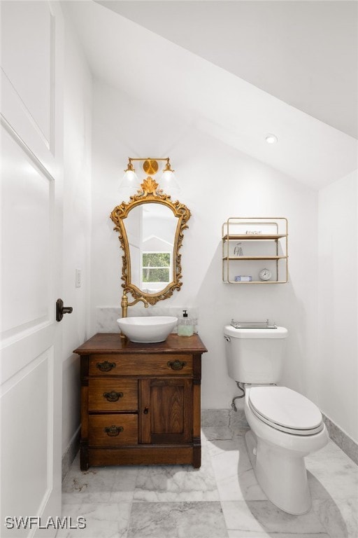 bathroom featuring vanity, toilet, and lofted ceiling