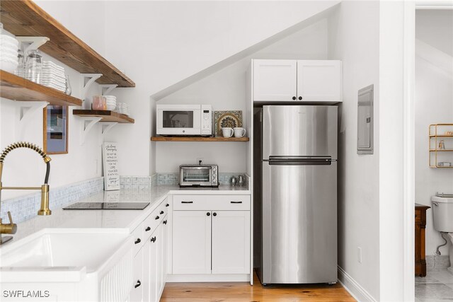 kitchen featuring white cabinets, stainless steel fridge, sink, and electric panel