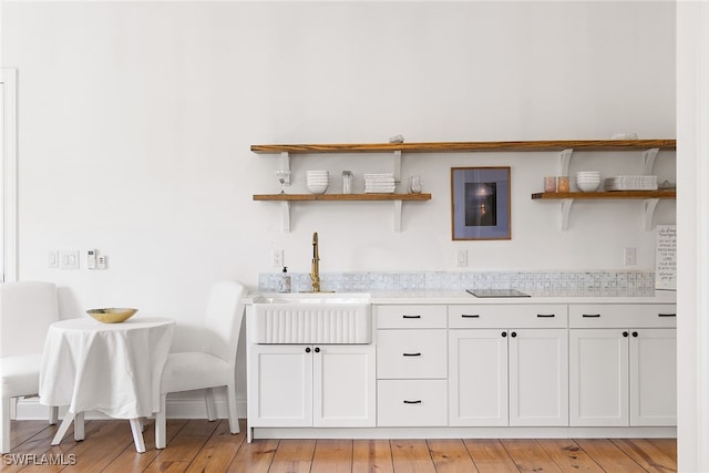 bar with white cabinets, light hardwood / wood-style flooring, and sink