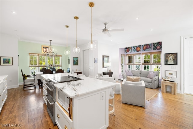 kitchen featuring a kitchen bar, pendant lighting, white cabinets, light hardwood / wood-style floors, and a kitchen island