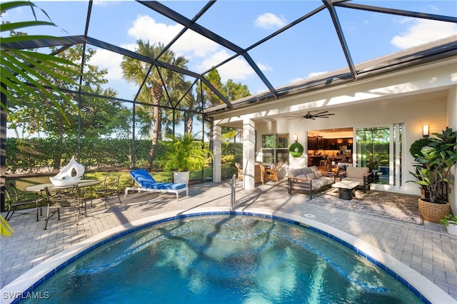 view of swimming pool featuring ceiling fan, an outdoor hangout area, a patio area, and glass enclosure