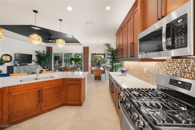 kitchen with sink, backsplash, hanging light fixtures, a notable chandelier, and stainless steel appliances