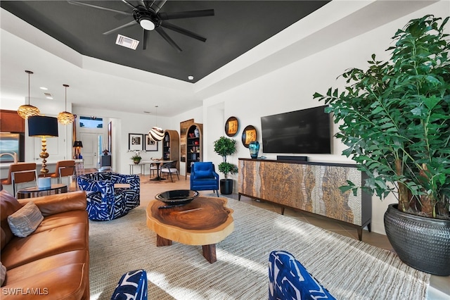 tiled living room with a tray ceiling and ceiling fan