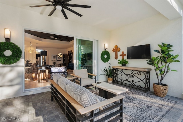 living room with a raised ceiling and ceiling fan