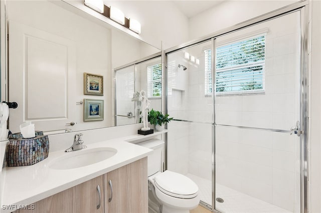 bathroom featuring vanity, a shower with shower door, and toilet