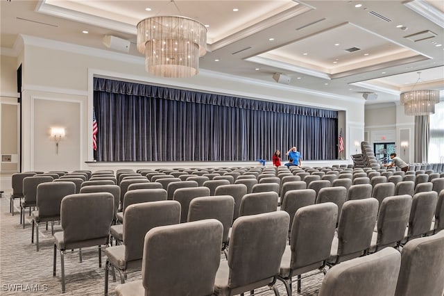 carpeted home theater with a tray ceiling, crown molding, and a chandelier