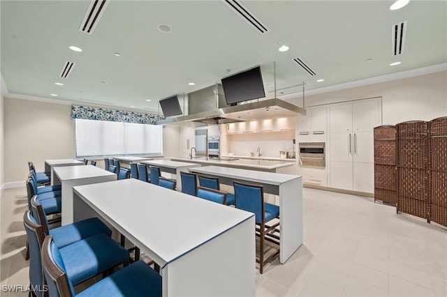 kitchen featuring a large island, white cabinetry, a kitchen breakfast bar, and oven