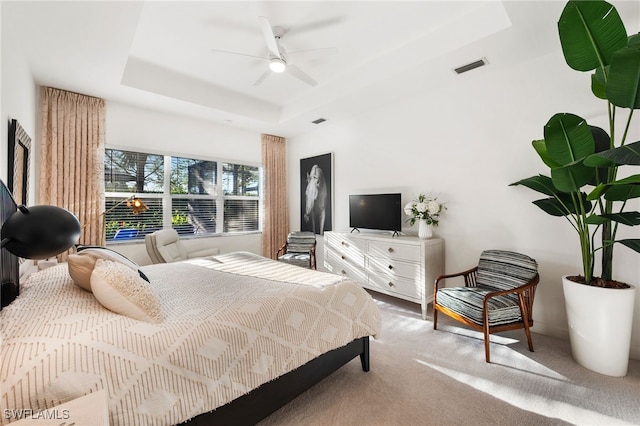 carpeted bedroom featuring ceiling fan and a tray ceiling