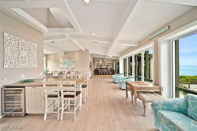 interior space with vaulted ceiling with beams, a water view, beverage cooler, and light hardwood / wood-style floors