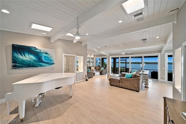 living room featuring lofted ceiling with beams, light wood-type flooring, a water view, and ceiling fan