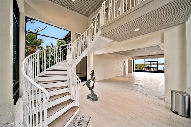 staircase with hardwood / wood-style floors and a towering ceiling