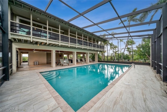 view of pool with glass enclosure, ceiling fan, and a patio