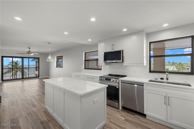 kitchen featuring appliances with stainless steel finishes, light wood-type flooring, a kitchen island, sink, and white cabinetry