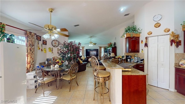 kitchen featuring kitchen peninsula, sink, light tile patterned floors, white refrigerator, and a breakfast bar area