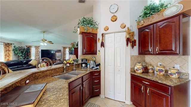 kitchen with backsplash, ceiling fan, sink, light tile patterned floors, and stone counters