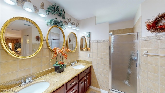 bathroom with a shower with door, vanity, and tile walls