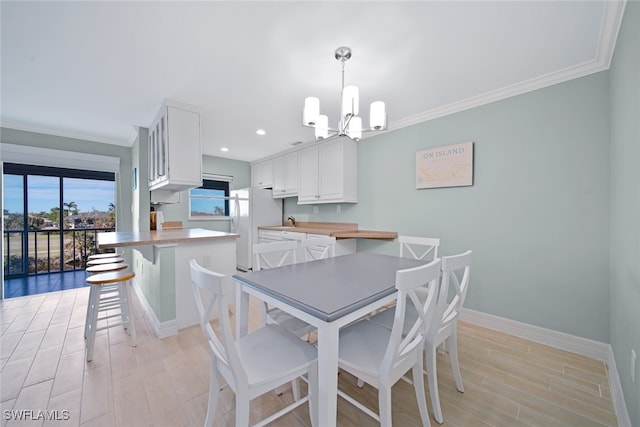 dining area featuring a notable chandelier, light wood-type flooring, and crown molding