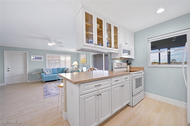 kitchen with white cabinetry, light wood-type flooring, white appliances, and a wealth of natural light