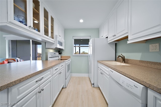 kitchen with white appliances, light hardwood / wood-style flooring, white cabinetry, and sink