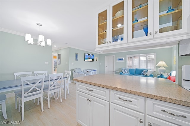 kitchen featuring ornamental molding, pendant lighting, a chandelier, light hardwood / wood-style floors, and white cabinetry