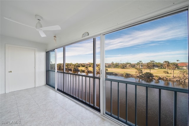 unfurnished sunroom featuring ceiling fan and a water view