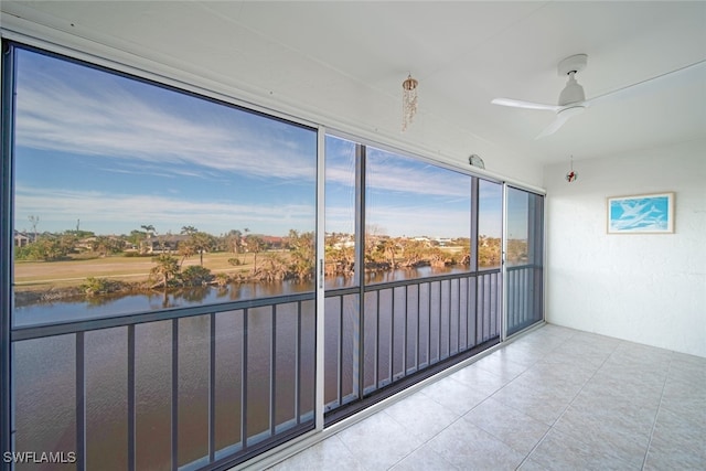 unfurnished sunroom with ceiling fan and a water view