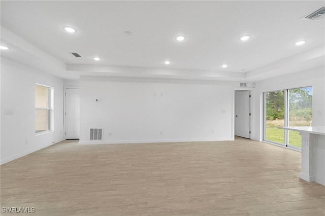 empty room featuring light hardwood / wood-style floors and a tray ceiling