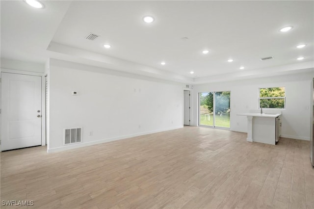 interior space with light hardwood / wood-style floors and a raised ceiling