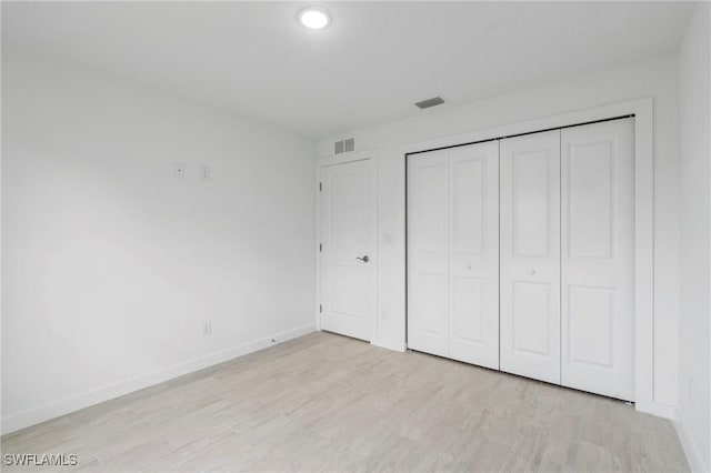 unfurnished bedroom with a closet and light hardwood / wood-style floors