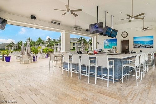 interior space featuring a breakfast bar, light wood-type flooring, and high vaulted ceiling