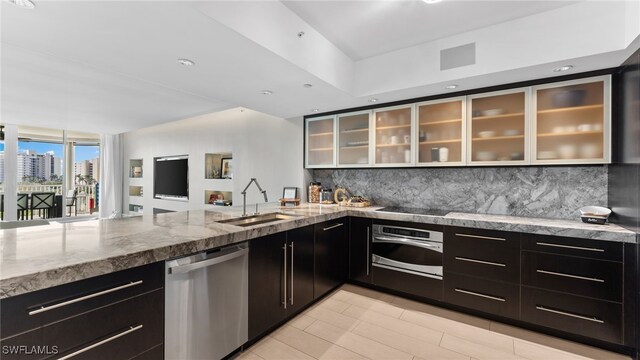 kitchen with backsplash, light stone counters, sink, and appliances with stainless steel finishes