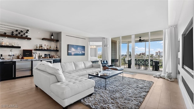 living room with indoor wet bar, floor to ceiling windows, light wood-type flooring, and ceiling fan