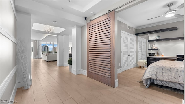 bedroom with a barn door, baseboards, light wood-style flooring, and crown molding