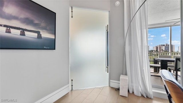 bedroom featuring a city view, light wood-type flooring, baseboards, and expansive windows