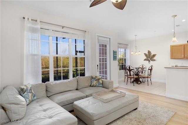 living room featuring light hardwood / wood-style floors and ceiling fan with notable chandelier