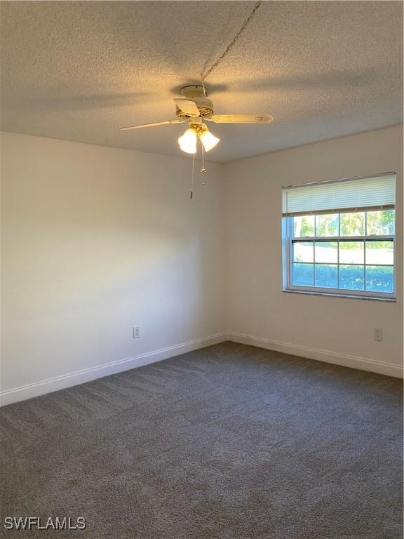7050 Nantucket Cir Unit 4, North Fort Myers, FL 33917 - spare room with a textured ceiling, dark carpet, ceiling fan, and baseboards